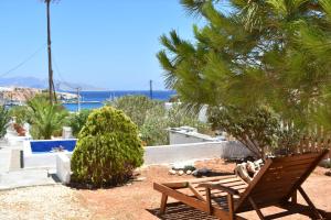 a wooden bench sitting next to a palm tree at Aegean Star Hotel in Karavostasi