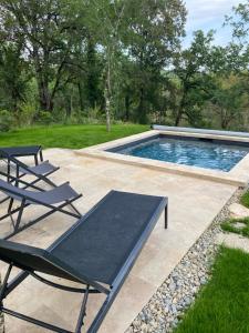 a swimming pool with two lounge chairs next to it at La Maison du Gindreau in Saint-Médard