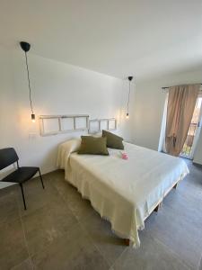 a white bedroom with a large bed and a chair at Relais PINF in Malcesine