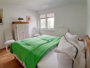 a bedroom with a bed with a green blanket on it at Ferienwohnung Schwalbennest in Juliusruh