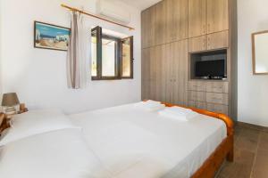 two white beds in a room with a tv at Stone house with Amazing View in Kótronas