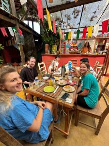 een groep mensen die rond een houten tafel zitten bij Mais Que Nada Itacaré - Hostel, Bar & Breakfast in Itacaré