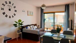 a living room with a couch and a clock on the wall at Cantinho do Sol - Sea view, Quiet, Cozy and Relaxing Flat in Armação de Pêra