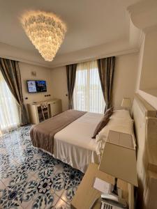 a hotel room with a large bed and a chandelier at Palace Hotel in Milano Marittima