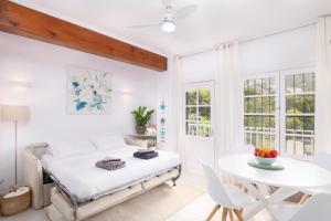 a white bedroom with a bed and a table at El Portet Moraira Apartment Ella in Moraira
