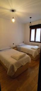 two beds in a bedroom with two windows at Apartamentos Casa de los ramos 2 in Vinuesa