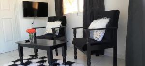 two black chairs and a table with a vase of flowers at Tropico Inn in Paramaribo