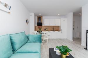 sala de estar con sofá azul y cocina en Apartamenty Mierzeja NCNK Baltic Twins Sztutowo, en Sztutowo