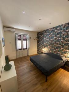 1 dormitorio con cama negra y suelo de madera en The First apartment en Cinisi