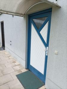 a blue door on a white building with a green mat at Ferienwohnung Morenz in Sinsheim