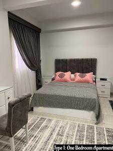 um quarto com uma cama com almofadas cor-de-rosa e uma cadeira em Luxury Apartments Beside Mall of Arabia and Dar Al-Fouad hospital - Families only- No Alcoholic Beverages em Cidade 6 de Outubro