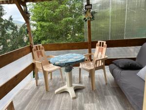 porche con mesa, 2 sillas y sofá en 2 à 4 pers appartement dans Maisonnette piscine chambre double salle de bain privatif, en Saint-Amarin