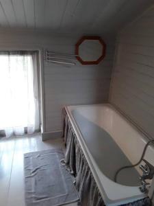 een badkamer met een wit bad en een raam bij Maison sur les bords de Vienne. in Queaux
