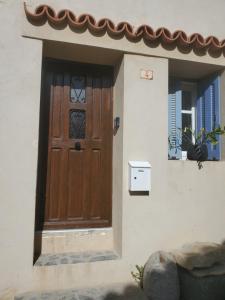 una puerta de madera en una casa con 2 ventanas en Corbara ,Pietralta, en Corbara