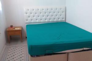 a green bed in a room with a table at Near the ladies beach only 200m in Kuşadası