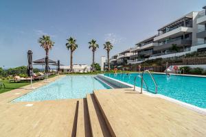 a large swimming pool with palm trees and a building at LME101A- Lovley Apartment with stunning views in Estepona
