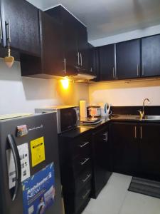 a kitchen with black cabinets and a sink at Spacious 2BR condo in Araneta Cubao in Manila