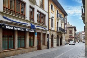 een straat met gebouwen en een auto die door een straat rijdt bij IRAIPE Ongi Hotel in Oñate