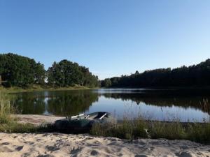 a boat sitting on the shore of a lake at OSTOJA PAWIE OKO in Potęgowo +39 photos