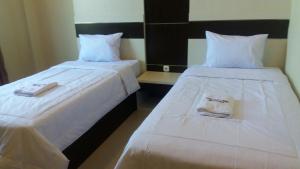 two beds sitting next to each other in a room at Galaxy Inn in Baubau