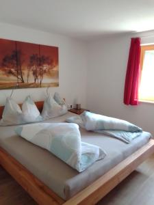 uma cama com lençóis brancos e almofadas em Ferienwohnung Maari em Hittisau