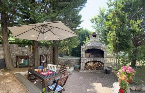 a patio with a table and an umbrella and a fireplace at Apartment Sersic in Baška