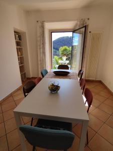 comedor con mesa, sillas y ventana en casa pungitopo, en Bedigliora