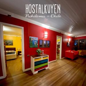 ein Wohnzimmer mit einer roten Wand und einem farbenfrohen Zimmer in der Unterkunft Hostal Kuyen in Pichilemu