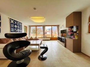 ein Wohnzimmer mit einem schwarzen Stuhl und eine Küche in der Unterkunft Ferienhaus Sissi in Schwangau