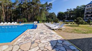 a swimming pool with chairs next to a building at Komfortowy Apartament w Blue Mare in Łukęcin