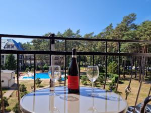 a bottle of wine sitting on a table with two glasses at Komfortowy Apartament w Blue Mare in Łukęcin