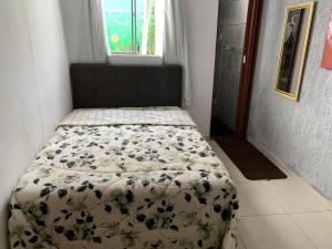 a bed in a small room with a comforter on it at Guest House do Magoo in Arraial do Cabo