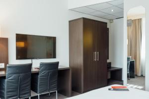 Elle comprend un bureau avec une télévision, un bureau et des chaises. dans l'établissement Leonardo Hotel Breda City Center, à Breda