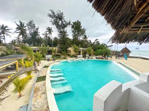 a swimming pool next to a beach with the ocean at Jambo Beach Hotel Paje in Paje