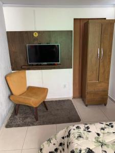 a living room with a chair and a tv at Guest House do Magoo in Arraial do Cabo