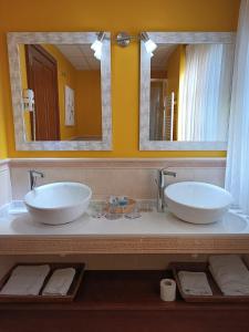 two sinks in a bathroom with two mirrors at Hotel Rural Foncubierta in Soto del Barco +11 photos
