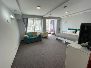 a bedroom with a bed and a couch and a tv at White Rose Guest Rooms in Burgas