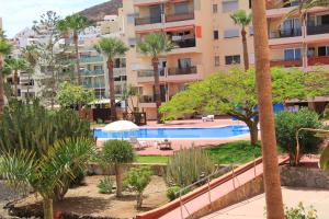 een uitzicht op een resort met een zwembad en palmbomen bij Trilocale moderno e centrale a Los Cristianos in Los Cristianos