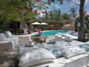Boutique Hotel Nyumbani Tembo في واتامو: مجموعة من الوسائد جالسة بجوار حمام السباحة