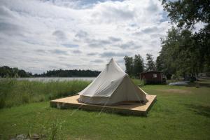 biały namiot siedzący na drewnianej platformie na polu w obiekcie Pukinsaaren Camping w mieście Kristinestad