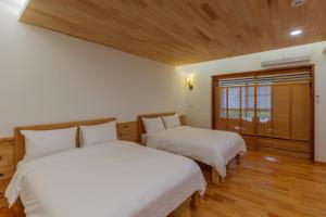 two beds in a room with wood floors and a window at Hou Shan Ren Jia B&B Hall A in Yung-an-ts'un