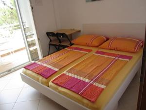 una cama con almohadas de color naranja y rosa encima en Apartments Roko en Rogoznica