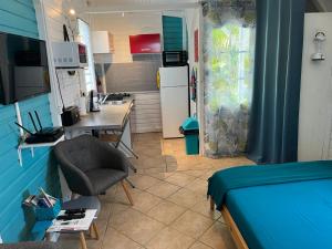 a room with a bed and a desk and a kitchen at Bungalow avec piscine in Sainte-Marie