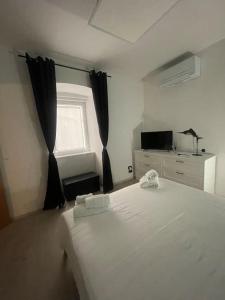 1 dormitorio con cama blanca y ventana en Casa Vacanze Viale Miramare 31- Delizioso mini loft industrial, en Trieste