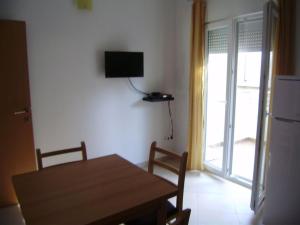 a dining room with a table and a television on the wall at Apartments Roko in Rogoznica