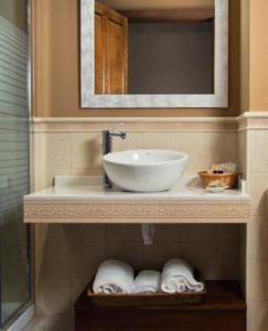 a bathroom with a sink and a mirror and towels at Hotel Rural Foncubierta in Soto del Barco