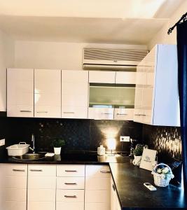 cocina con armarios blancos y encimera negra en City Square Apartment, en Poreč