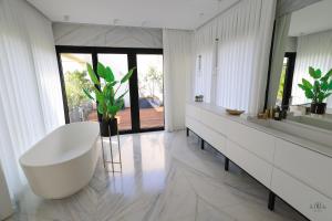 bagno con vasca bianca e grande specchio di Breathtaking Villa w Pool & Sauna Near the Beach by Sea N' Rent a Herzelia