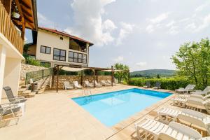 a swimming pool with lounge chairs and a house at Jankovi Dvori in Rakovica
