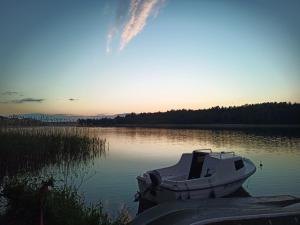 a boat sitting on a lake at sunset at DOM LETNISKOWY NAD JEZIOREM Łódż wiosłowa i kajak in Wilkasy